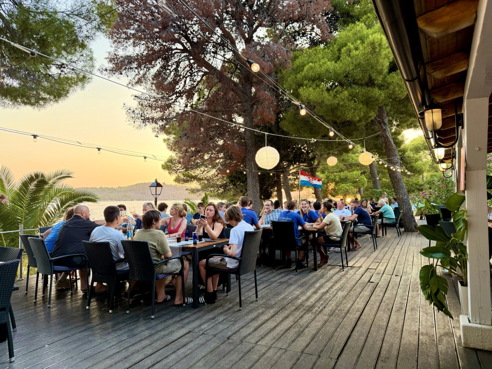 Terrace dining under string lights as the sun sets over the sea