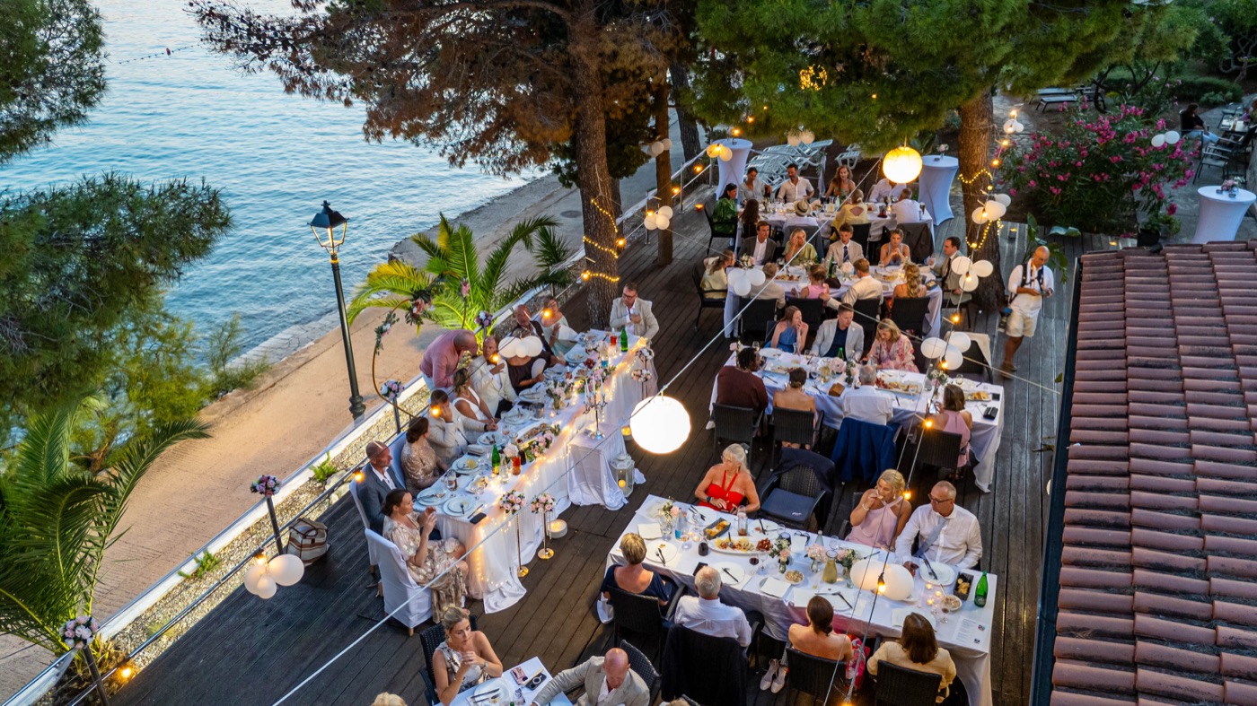 Aerial view of guests dining on the seafront terrace at dusk